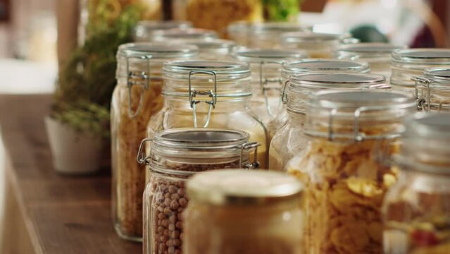 Close up on bulk products in recyclable glass containers used by zero waste supermarket to eliminate single use plastics. Local store pantry staples in sustainable packaging, zoom out shot