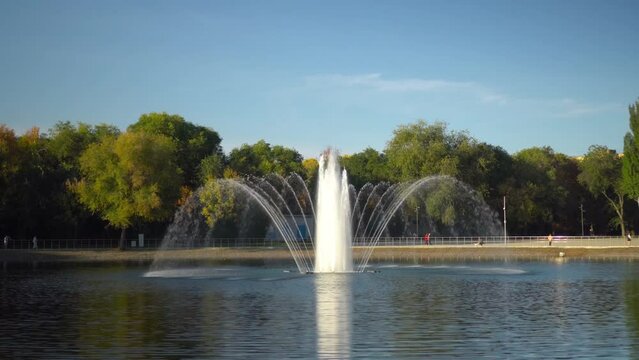A fountain in a park in the middle of a lake.
