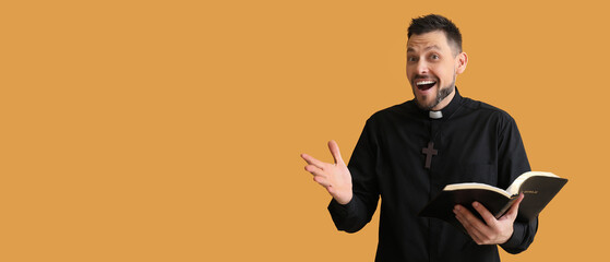 Happy priest holding Bible on orange background with space for text