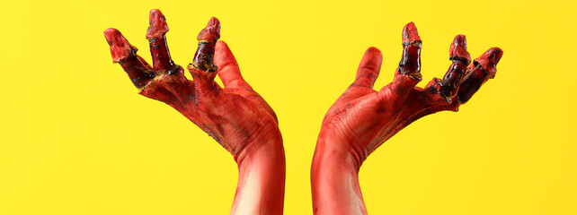 Bloodstained zombie hands on yellow background. Halloween celebration