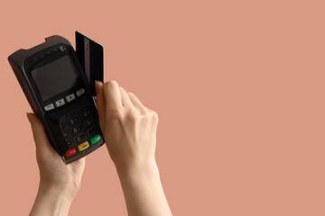 Woman with credit card and payment terminal on color background