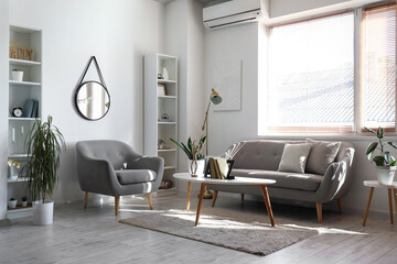 Interior of light living room with sofa, armchair and table