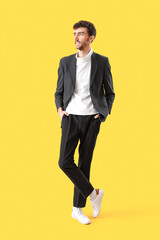 Young man in suit on yellow background