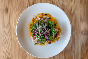 Fresh crispy salad with vegetables and seafood (shrimps) in a white plate on a light background. Healthy food concept.