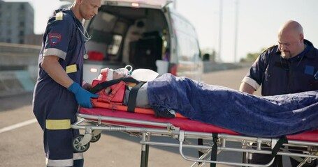 Road accident, paramedic and a person on a stretcher for medical attention, healthcare or an injury. First aid, help and an ambulance with an emergency patient in the street for danger or trauma