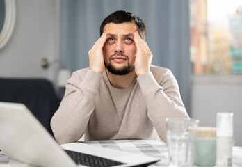Man experiencing headache after working long hours on laptop at home
