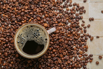 Cup of coffee and scattered beans on beige tile background