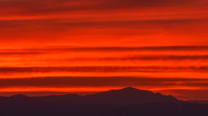 Fototapeten Orange warm colorful sky from sunset over silhouette of mountain landscape © Sebastian