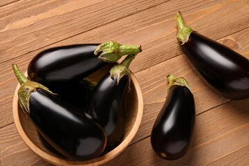 Bowl with fresh eggplants on wooden background