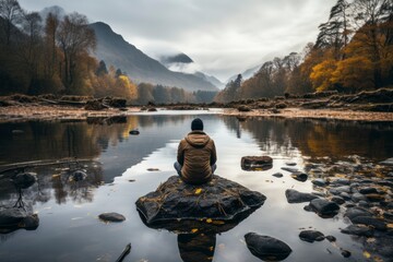 A contemplative image of a person staring out into the horizon at a tranquil lake, conveying a sense of solitude and inner reflectio