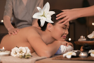 Obraz na płótnie Canvas Young woman having massage in dark spa salon