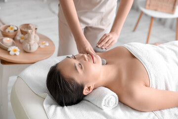 Young woman undergoing treatment with stones in spa salon, closeup