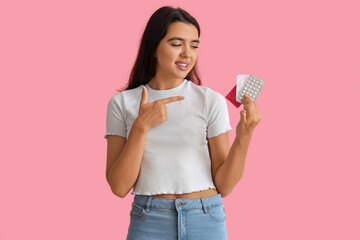Young woman with different means of contraception on pink background