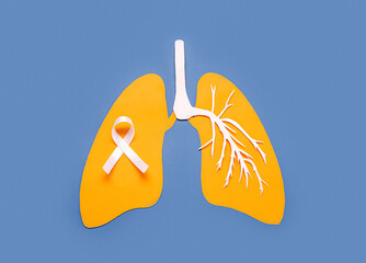 Paper lungs with white ribbon on blue background. Lung cancer concept