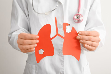 Doctor holding red paper lungs on light background. Cancer concept
