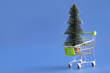 Shopping cart with Christmas tree on blue background
