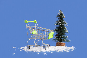 Shopping cart with Christmas tree and snow on blue background