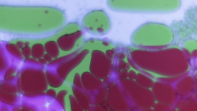 ミクロの世界では、緑と赤の液体の泡が勢いよく渦を巻く
