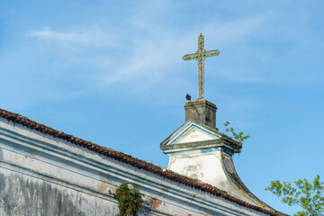 A black vulture standing beneath the cross of an old church. Abandoned place.