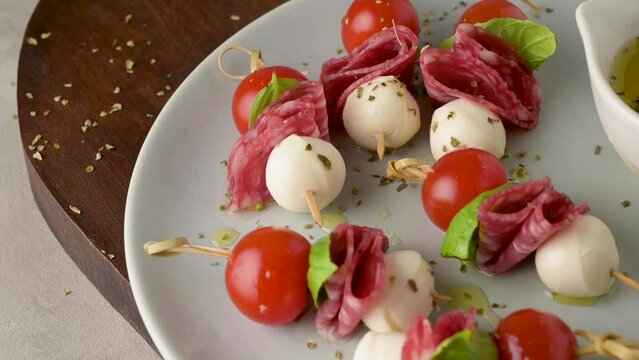 Italian style appetizer, antipasto skewer or caprese on a stick with basil, salami, mozarella and tomatoes.