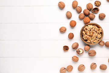 Bowl with tasty walnuts on white wooden background