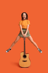 Obraz premium Pretty young woman with acoustic guitar on orange background