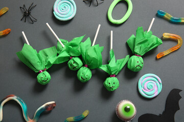 Sweet lollipops for Halloween party with jelly worms and eye on black background