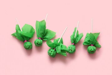 Sweet green lollipops for Halloween party on pink background