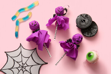 Sweet lollipops with jelly worms and liquorice for Halloween party on pink background