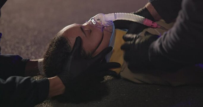 Accident, patient and neck brace by face with hands, night and paramedic for medical service. Victim, closeup and saving or rescue from disaster, first aid and cpr and oxygen mask for drunk driving