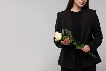 Woman with white rose flowers on light grey background, closeup and space for text. Funeral ceremony