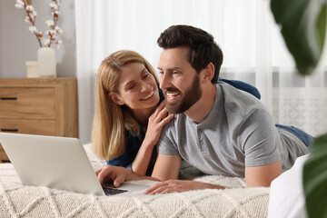 Fototapeta premium Happy couple with laptop on bed at home