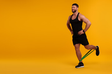 Fototapeta na wymiar Young man exercising with elastic resistance band on orange background. Space for text