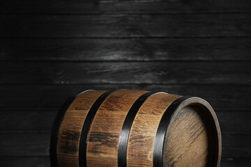 One wooden barrel near dark wall, closeup. Space for text