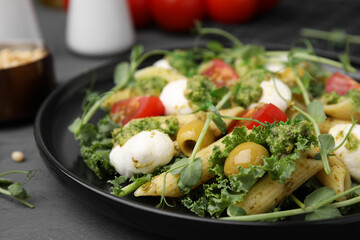 Delicious pesto pasta salad on gray table, closeup