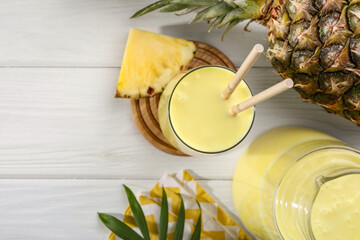 Tasty pineapple smoothie and fruit on white wooden table, flat lay. Space for text