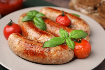 Plate with tasty homemade sausages, basil leaves and tomatoes, closeup