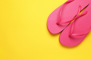 Stylish pink flip flops on yellow background, top view. Space for text