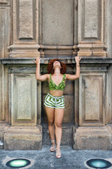 Portrait of a beautiful red-haired woman standing leaning against a wall in a church.