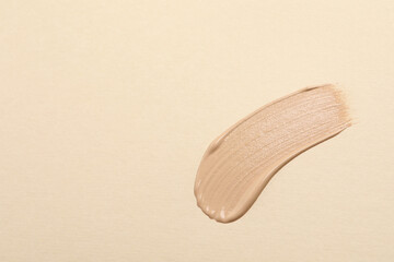 Smear of skin foundation on beige background, top view. Space for text