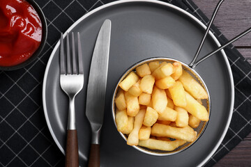 Tasty french fries and ketchup served on wooden table, flat lay