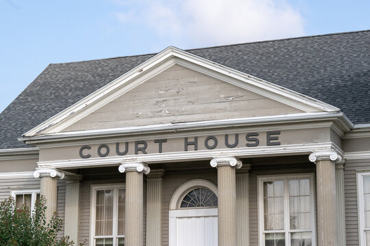 A Wide Brick Entrance To A Large Vintage Courthouse, Justice, Or Government Style Building.  The Words Court House Are Over The White Door Entrance And Round Pillars Of The Front Of The Old Building. 