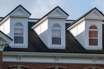 Three peaked dormer-style windows on a hip roof covered with black shingles. The vintage white...