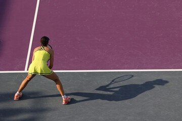 Female tennis player in action on the court on a sunny day, preparing to receive serve