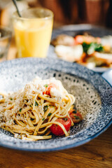 Linguine with fresh tomatoes, basil and freshly grated parmesan cheese, outdoor brunch, orange juice in the background.