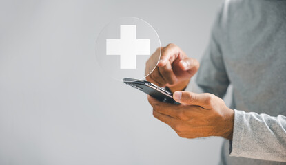 Man hand holds smartphone with plus icon, representing healthcare and medical benefits. Health...