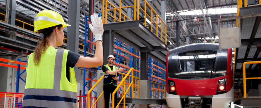 Young caucasian engineer woman or worker signal while engineer man checking electric train for planning maintenance in station, transport and infrastructure, inspector check service transport.