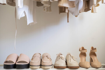 Women's seasonal autumn and spring shoes in the closet at home. Shoes and clothes in beige and neutral colors.