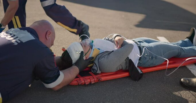 Hands, emergency oxygen and a paramedic group with a patient or victim on the street for accident treatment. Healthcare, medical or first aid with a professional emt team working to rescue a person