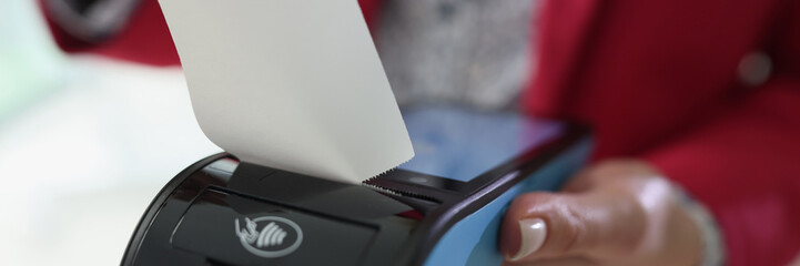 Woman holds terminal in hand tearing off purchase receipt